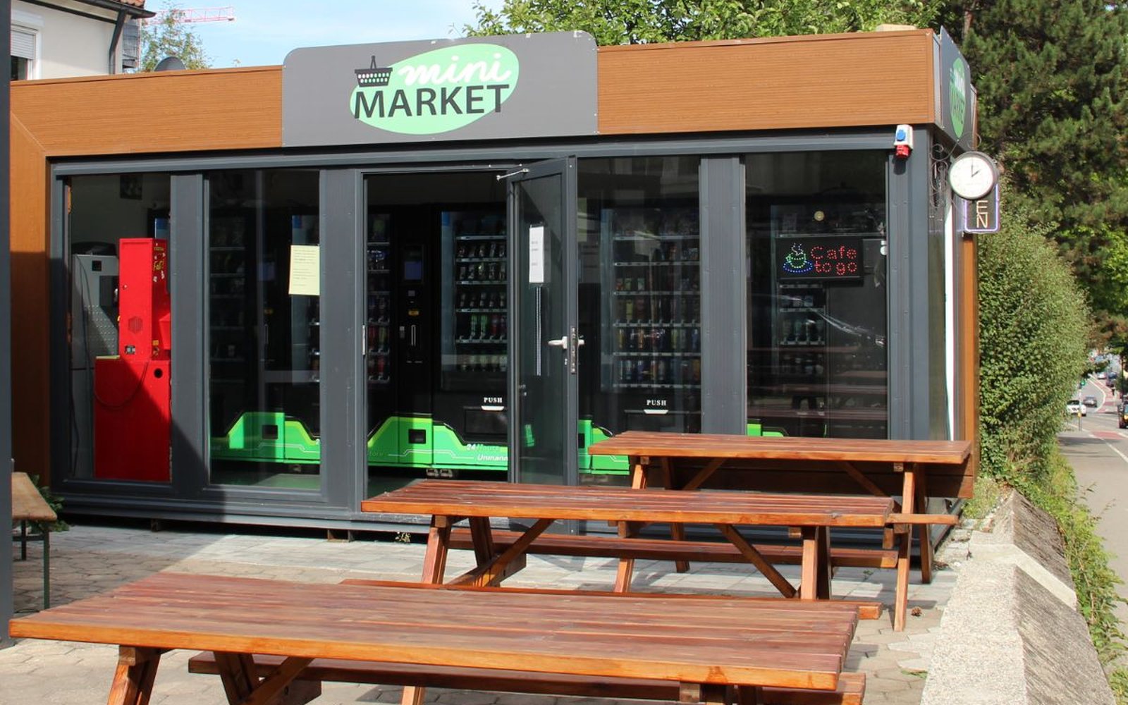 Die verglaste Front des Mini Market mit Sitzbänken davor